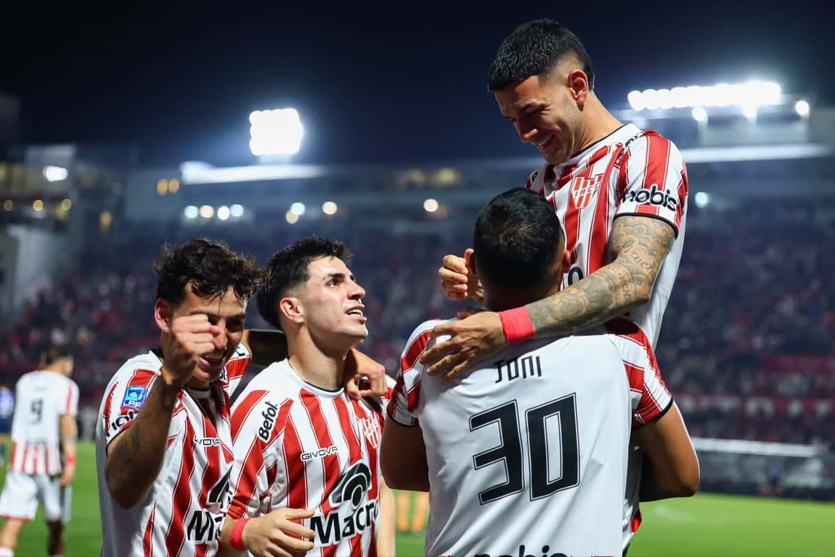 Jugadores de Instituto, con la camiseta albirroja, festejan abrazados un gol en Alta Córdoba durante el Clausura 2026