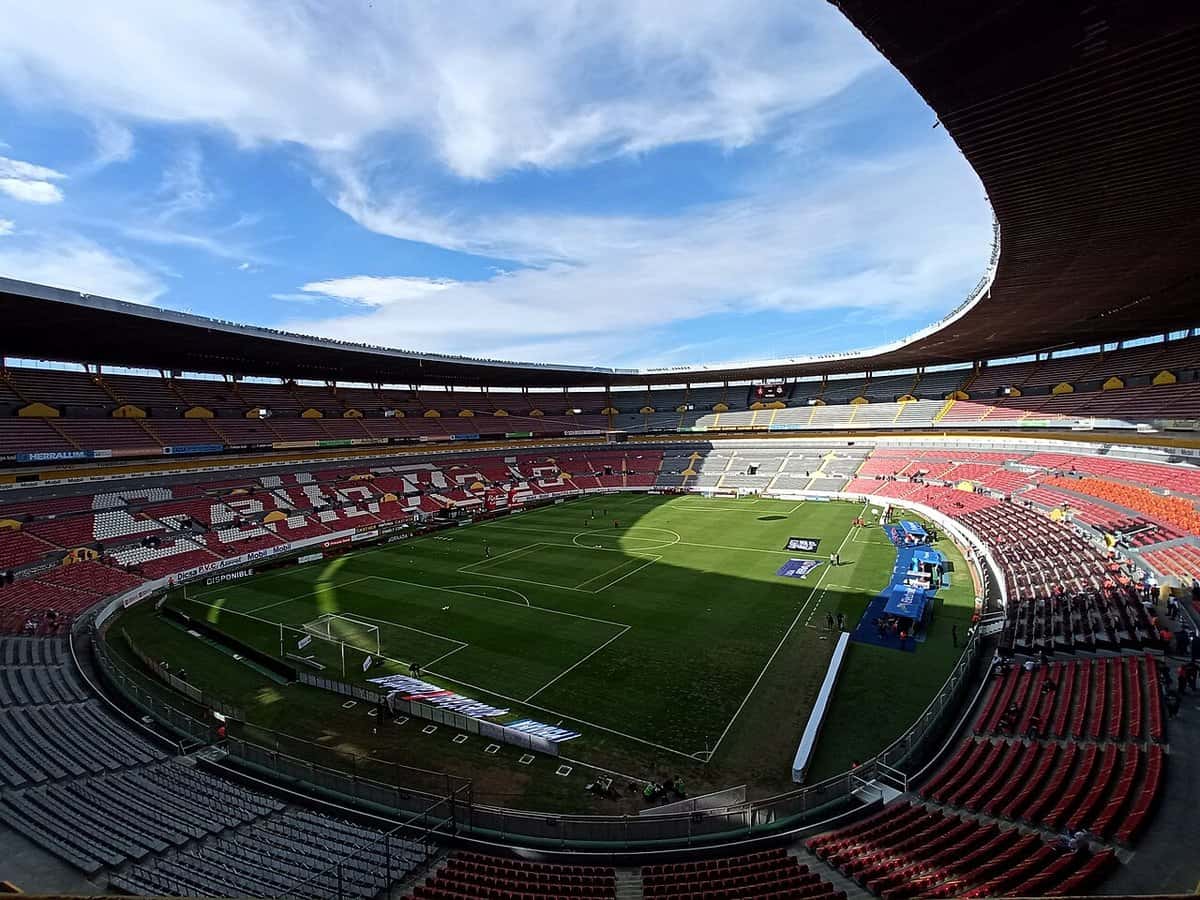 El estadio Jalisco, en Guadalajara, antes de un partido del Atlas, con las tribunas rojas y el campo de juego iluminado por el sol; foto de archivo de 2022 (foto: Alejan98, Wikimedia Commons, dominio público CC0)