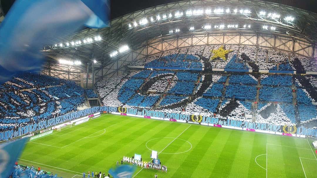 El interior del estadio Vélodrome, con la tribuna cubierta por un mosaico celeste y blanco de los hinchas del Marsella antes de un partido; foto de archivo de abril de 2015 (foto: Hombrey, Wikimedia Commons, licencia CC BY-SA 4.0)