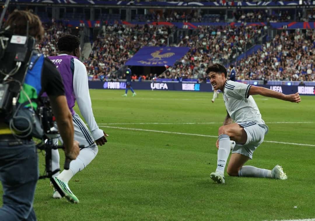 Alessandro Bastoni festeja de rodillas su gol del empate ante Francia, con la tribuna del Stade de France de fondo