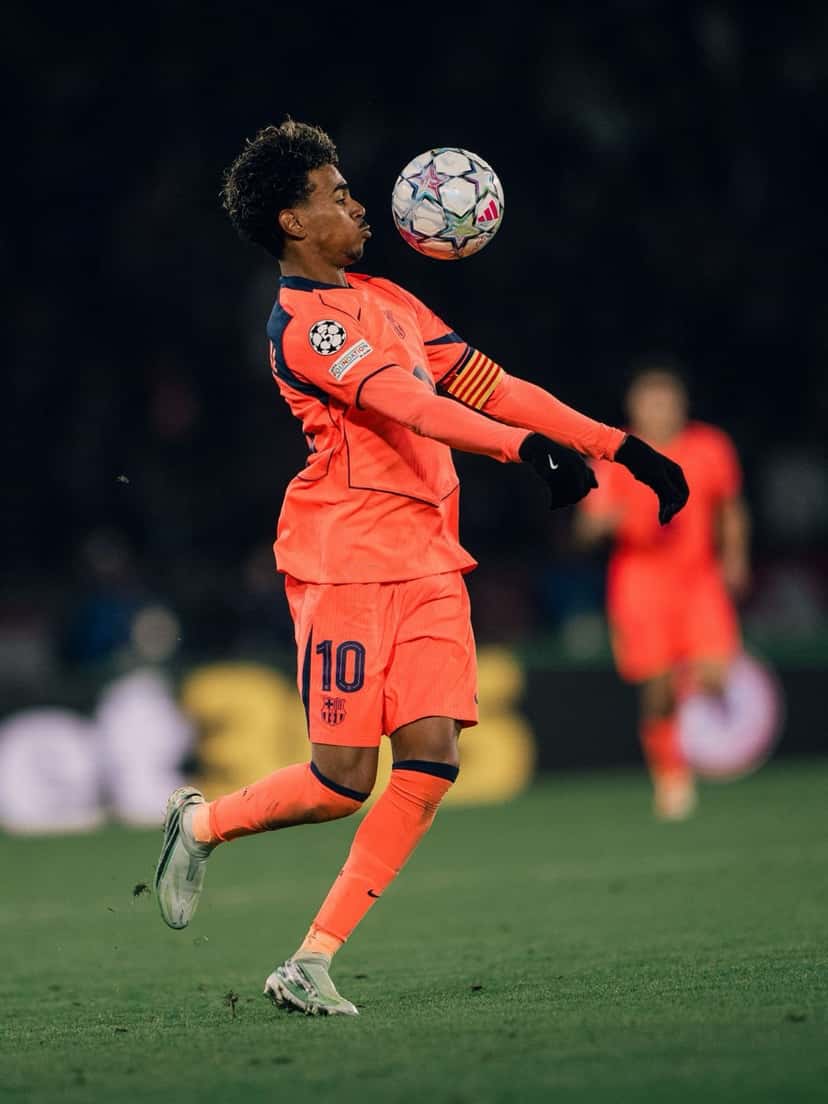 Lamine Yamal, con la camiseta naranja del Barcelona, el número 10 y la cinta de capitán, controla la pelota con el pecho durante el partido con el PSG (foto: FC Barcelona)
