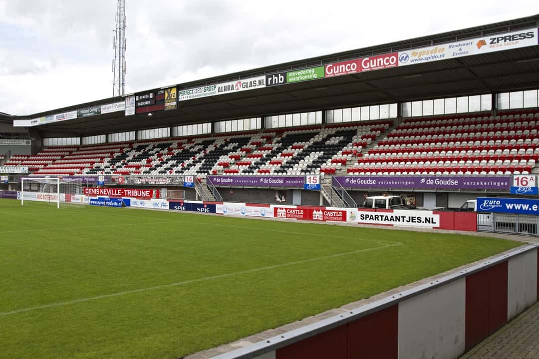La tribuna del estadio Het Kasteel, con butacas rojas, blancas y negras, vista desde el borde de la cancha; foto de archivo de agosto de 2012 (foto: Dick Aalders, Wikimedia Commons, licencia CC BY-SA 2.0)