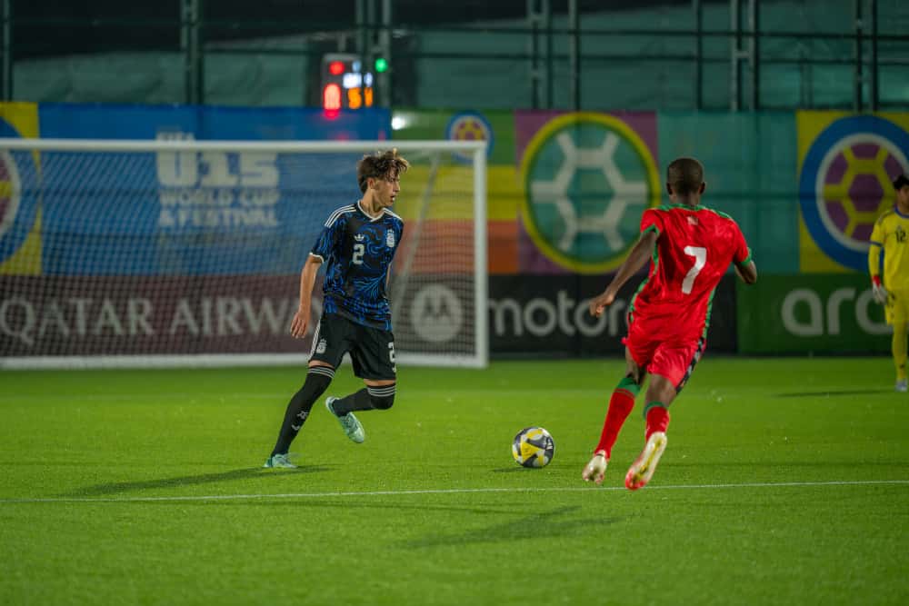 Un jugador de la Selección argentina Sub-15, con camiseta azul oscura, avanza con la pelota ante un rival de camiseta roja en el Complejo de Competición Hovsan, en Bakú (foto: prensa oficial de la AFA)