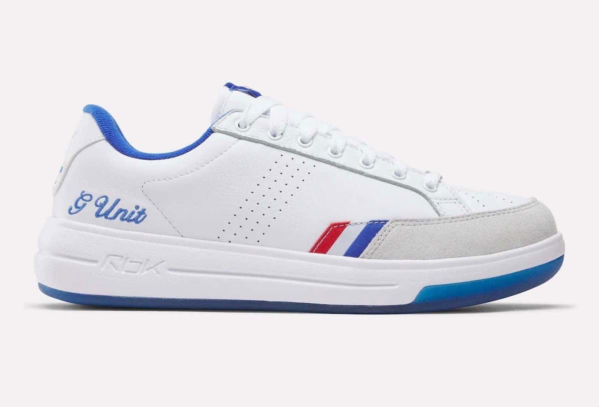 Reebok G-Unit G6 de perfil, en cuero blanco con gamuza gris en la puntera, franjas rojas, blancas y azules, G Unit bordado en azul en el talón y suela azul