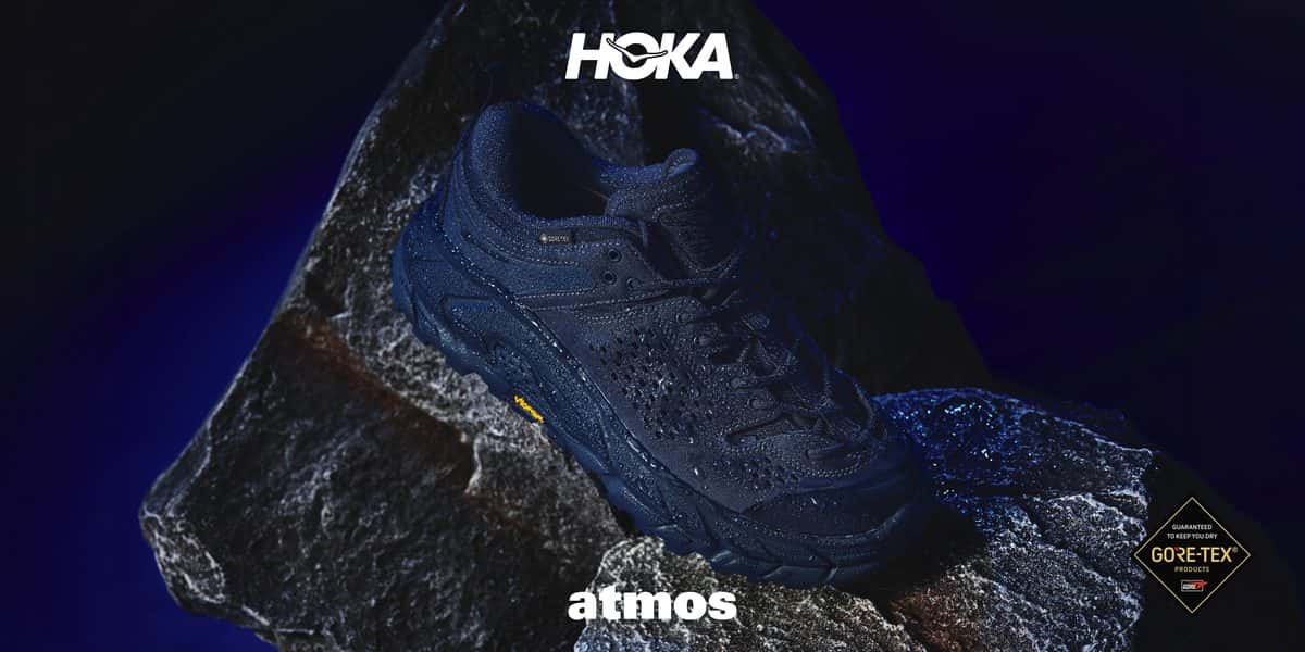 HOKA Tor Ultra Lo azul marino exclusiva de atmos apoyada sobre una roca, con los logos de HOKA, atmos y GORE-TEX