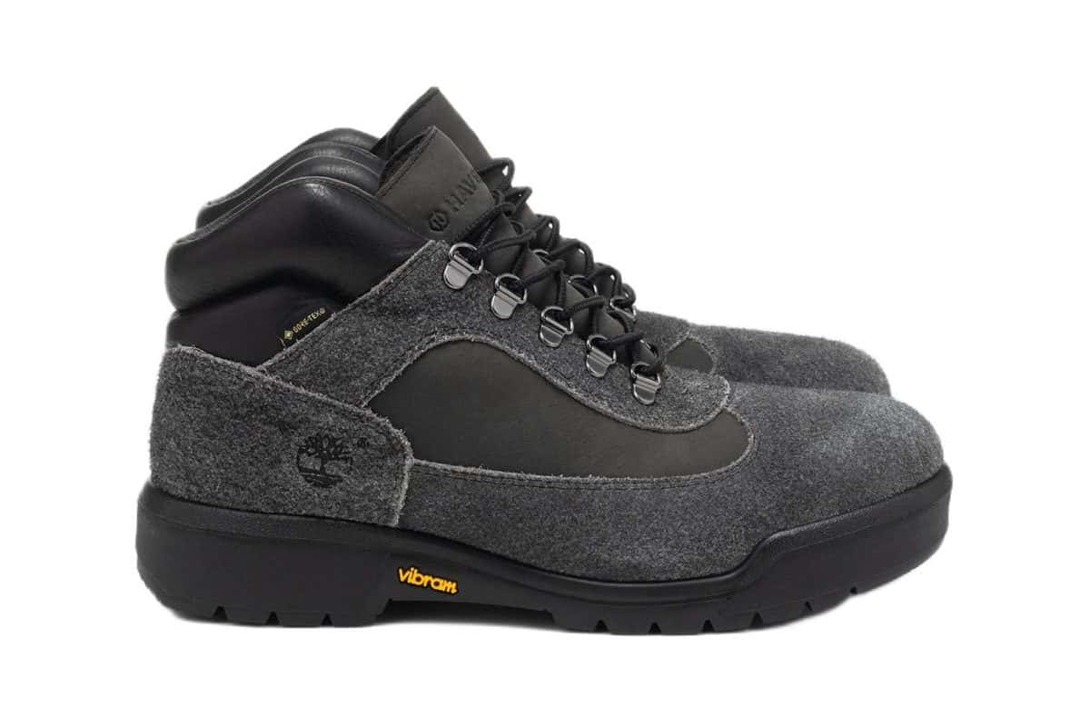 HAVEN x Timberland Field Boot de perfil sobre fondo blanco, con gamuza de pelo largo gris oscuro, paneles negros, ojales metálicos y la suela negra Vibram