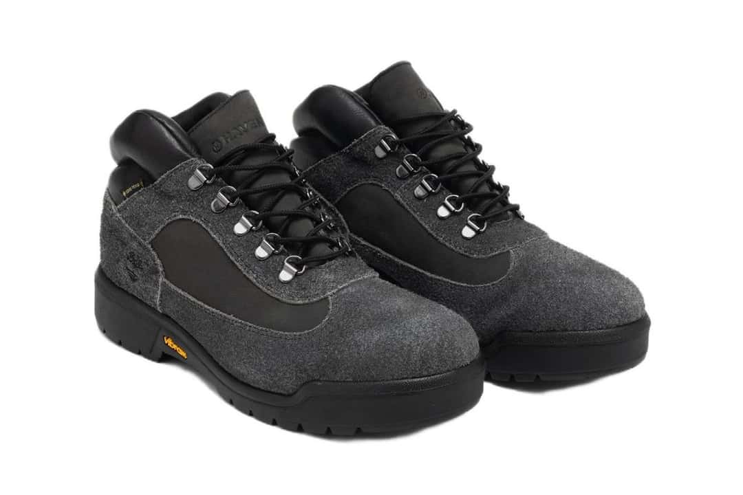 Par de la HAVEN x Timberland Field Boot en vista de tres cuartos, con la gamuza de pelo largo gris oscuro, los cordones negros y los ojales metálicos