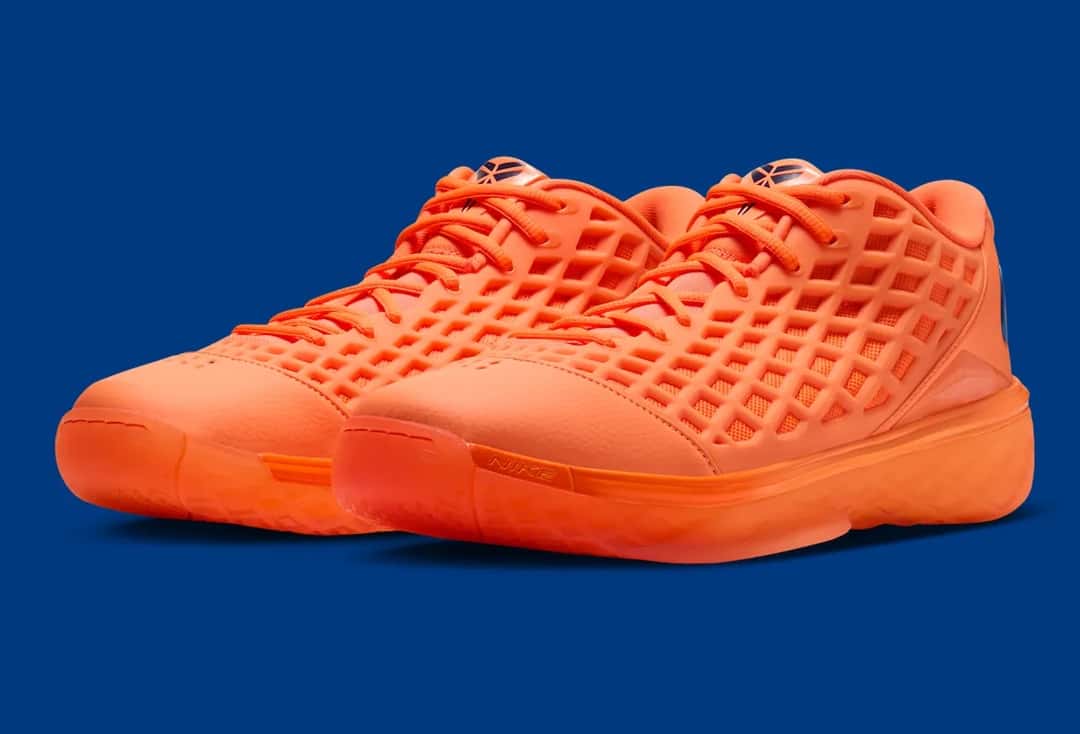 Par de Nike Kobe 3 Low Protro Arancia en diagonal, con la capellada naranja texturada y la suela naranja translúcida, sobre fondo azul