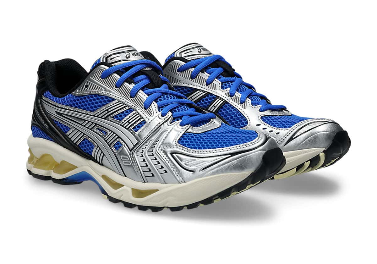 Par de ASICS GEL-Kayano 14 Illusion Blue Pure Silver en diagonal sobre fondo blanco, con malla azul eléctrico, capas plateadas metalizadas, cordones azules, talón negro y mediasuela crema con GEL amarillento