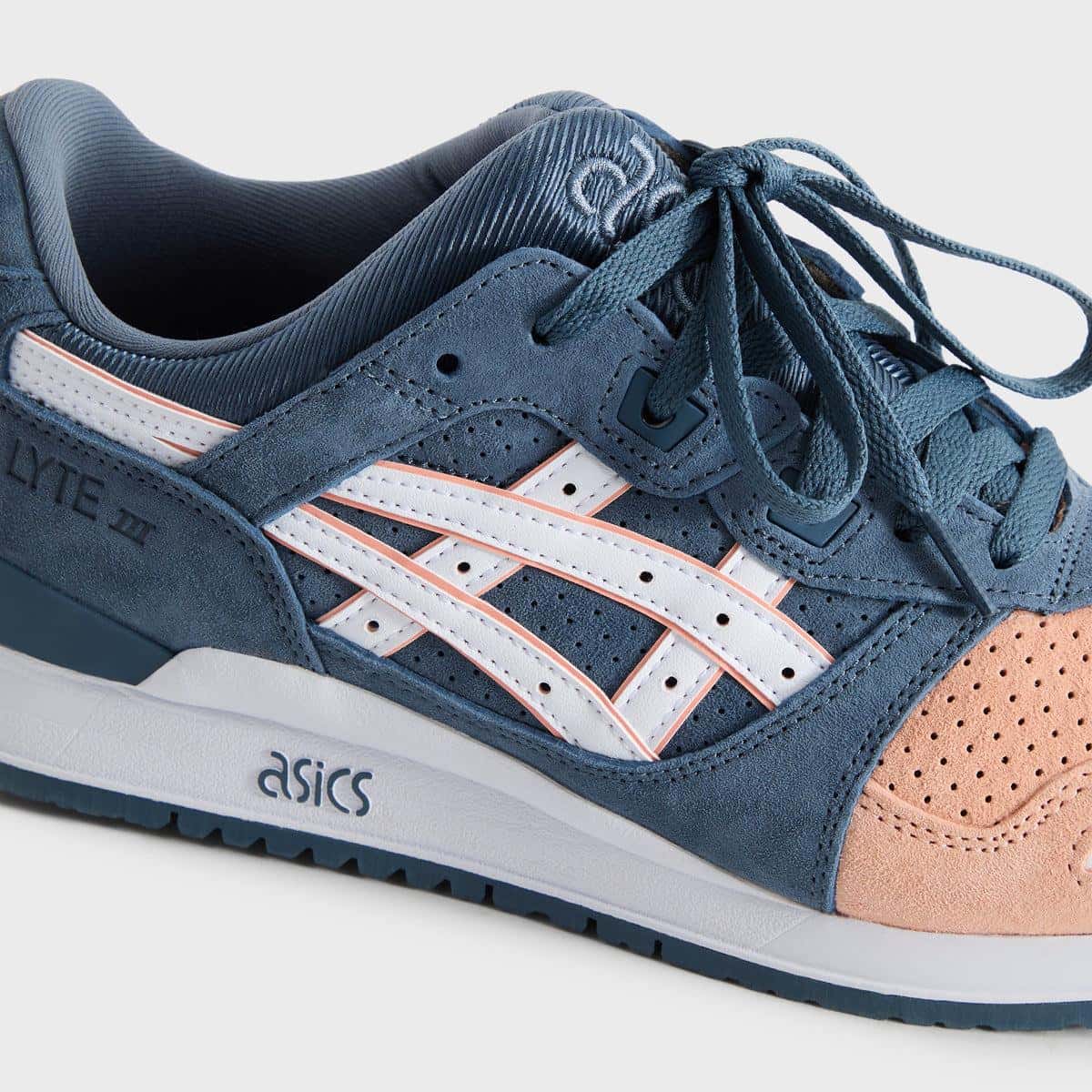 Primer plano lateral de la Kith x ASICS GEL-LYTE III Remastered Salmon Toe con nubuck azul perforado, rayas ASICS blancas con vivo salmón y puntera salmón