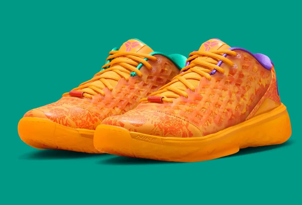 Par del Nike Kobe 3 Low Protro Mamba Eterno en diagonal sobre fondo verde agua: upper naranja con estampado floral rojo debajo de la jaula translúcida, cuello violeta en un pie y verde agua en el otro, y suela naranja