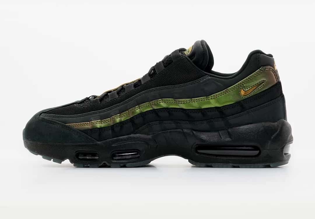 Kyle Wilson x Nike SB Air Max 95 negro visto desde el lado interno sobre fondo gris claro, con la franja verde metalizada, la puntera de gamuza negra y la unidad Air oscura a la vista