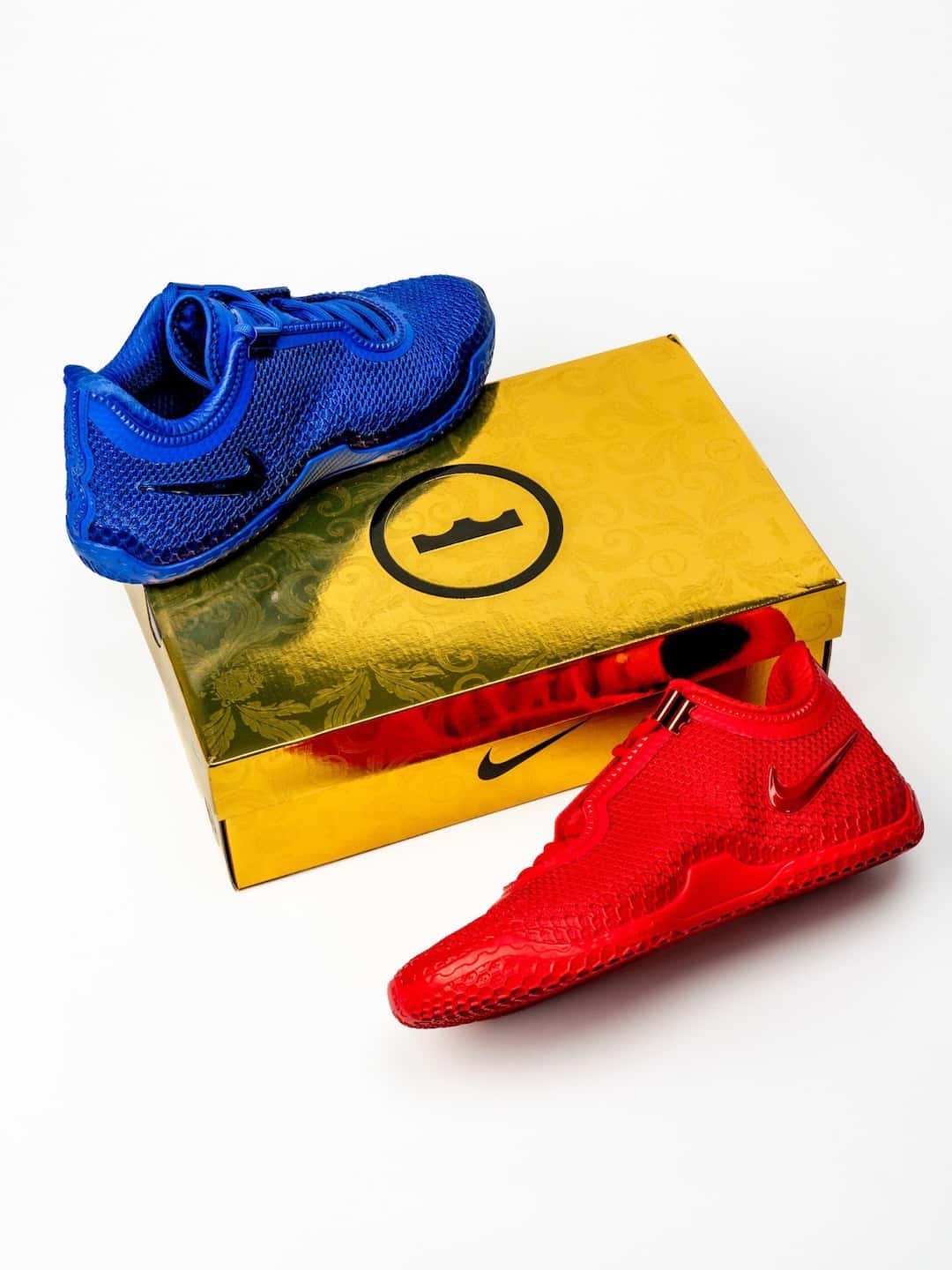 Nike LeBron 24 Philly azul arriba de una caja dorada y la roja saliendo de la caja, sobre fondo blanco