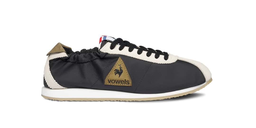 Vista lateral de la vowels x Le Coq Sportif Wendon negra con parche triangular de gamuza oliva y talón elastizado