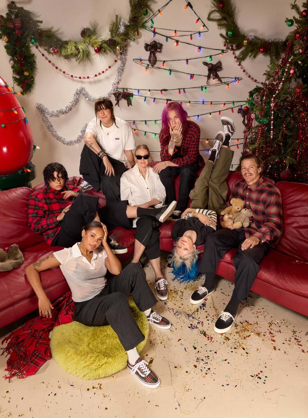 Foto de grupo de la campaña Meet The Vans de Vans en un living decorado con guirnaldas y luces de Navidad, con varias personas sentadas en un sillón rojo y en el piso