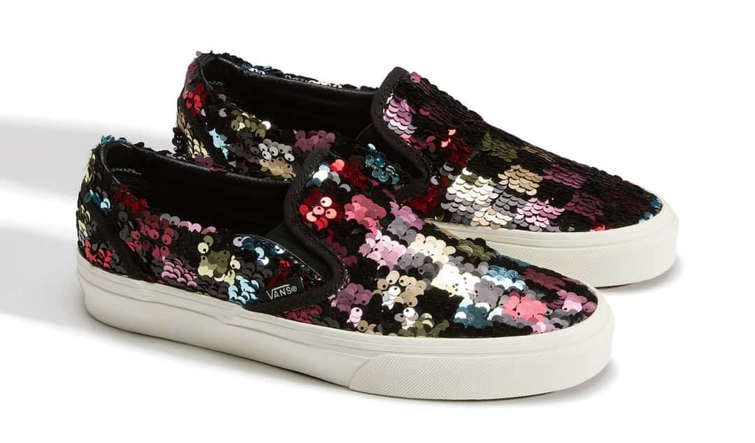 Par de Vans Classic Slip-On cubiertas de lentejuelas de colores sobre fondo negro, con suela blanca