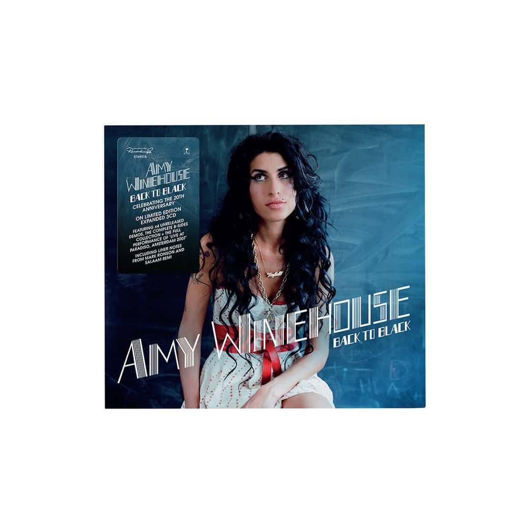 Portada de la edición aniversario de «Back to Black» de Amy Winehouse: Amy sentada frente a una pared azul, con vestido claro, cinturón rojo y el pelo suelto, y el nombre de la artista en letras blancas