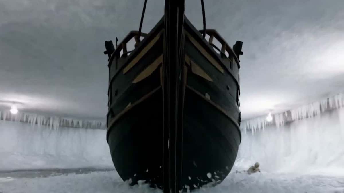 Imagen del teaser oficial "CRASH TO BEGIN" de ATEEZ: la proa de un velero oscuro avanza dentro de una cueva de hielo con estalactitas y luces blancas
