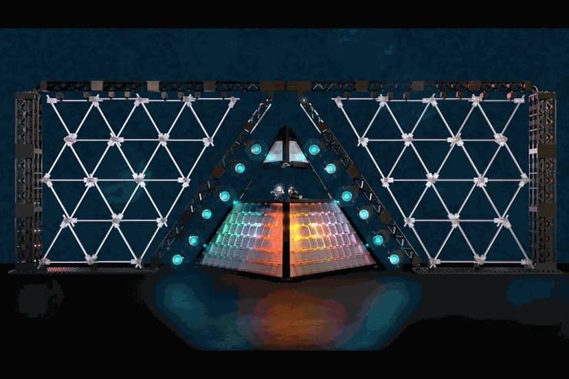 El diseño original de la pirámide de Daft Punk presentado en LEGO Ideas: el escenario con forma de triángulo, con paneles de luces y una estructura de triángulos a los costados, iluminado sobre fondo oscuro