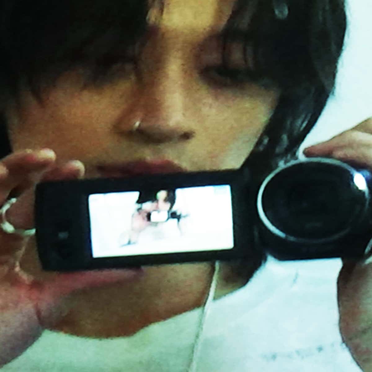 Portada del single «MISS ME», de keshi: el cantante, de pelo oscuro, sostiene frente a su cara una cámara de video con la pantalla abierta