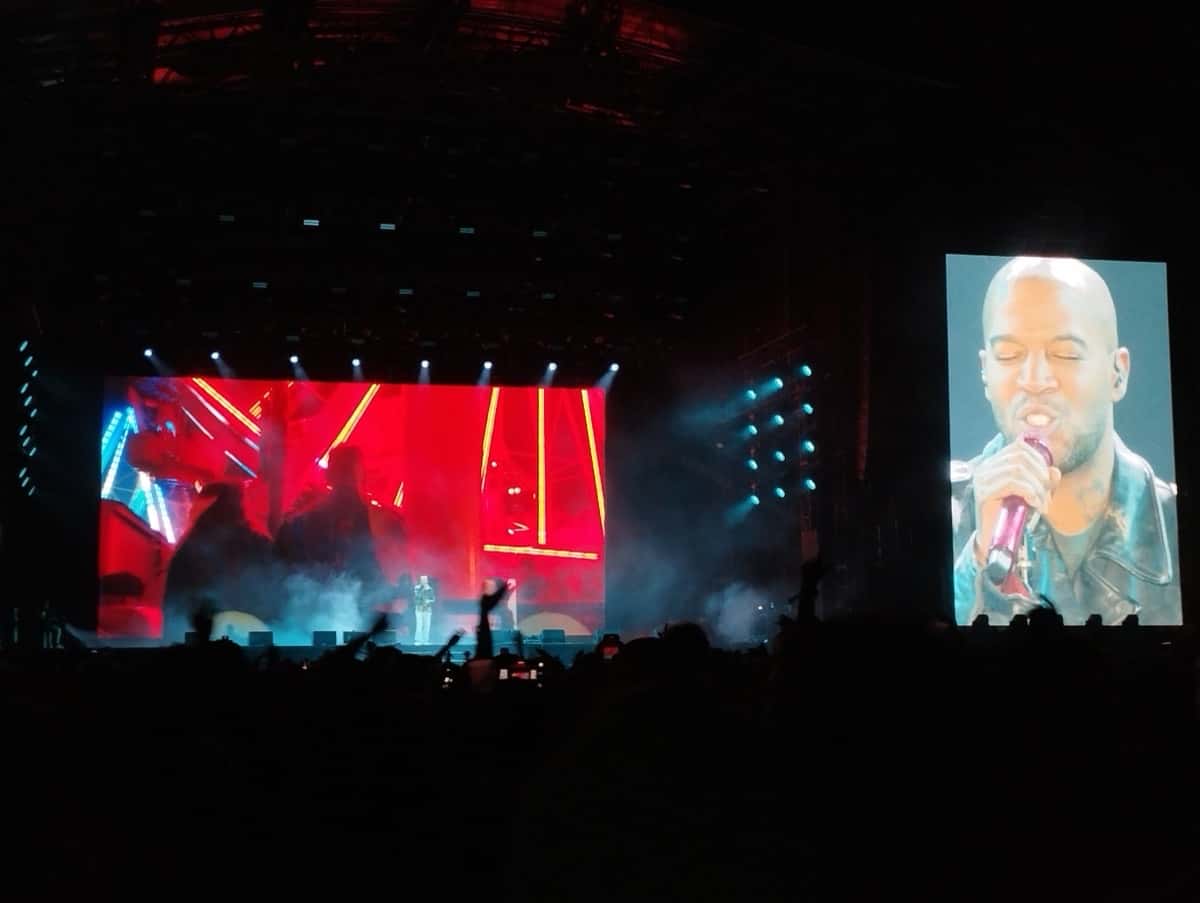Kid Cudi en vivo en Rock en Seine, en agosto de 2025: el escenario a oscuras con pantallas rojas y luces celestes, y a la derecha una pantalla gigante con un primer plano del rapero cantando (foto de archivo). Foto: ManoSolo13241324, CC0, vía Wikimedia Commons