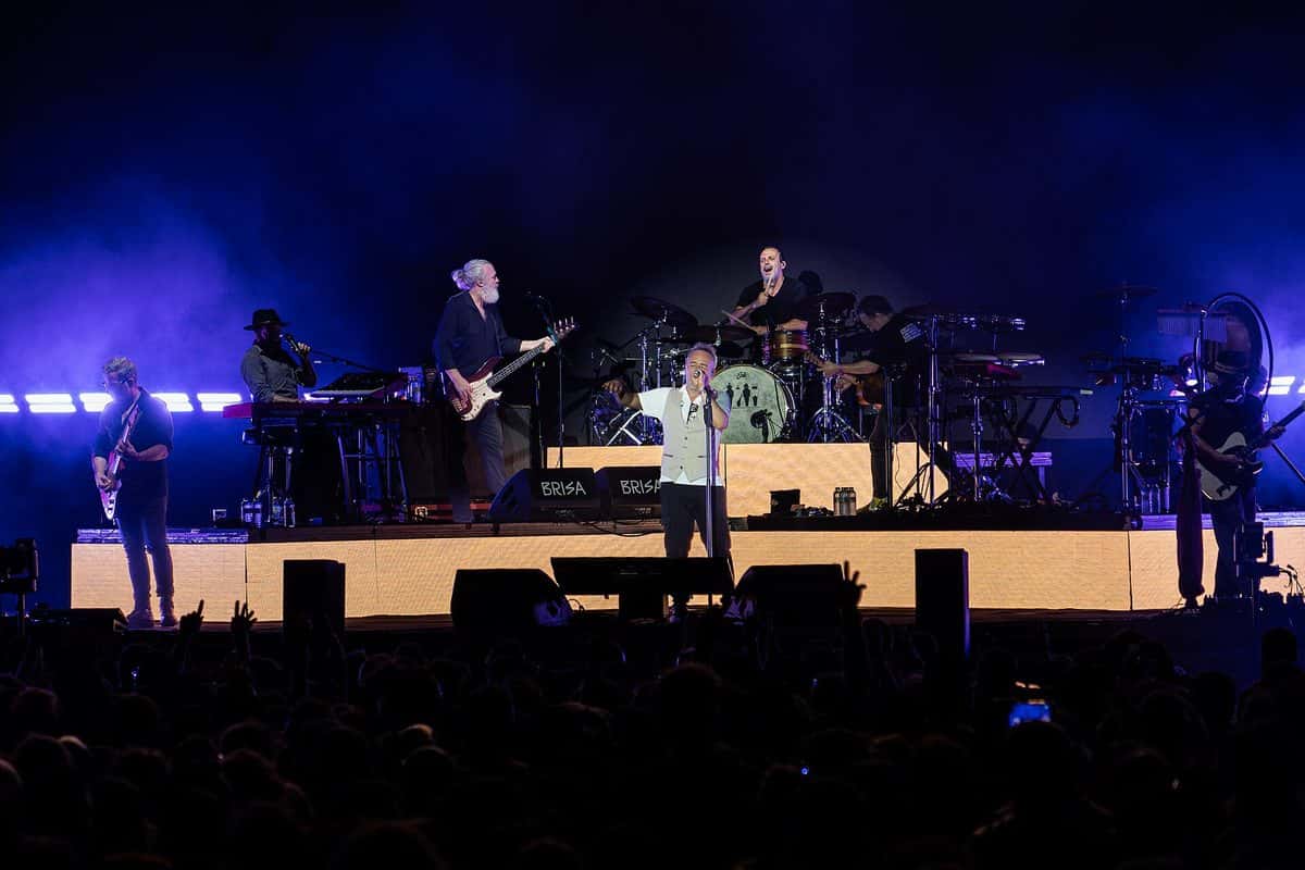 Love of Lesbian toca en el escenario del Brisa Festival, con Santi Balmes al centro y la banda iluminada en azul y violeta, frente al público (foto de archivo, julio de 2026)