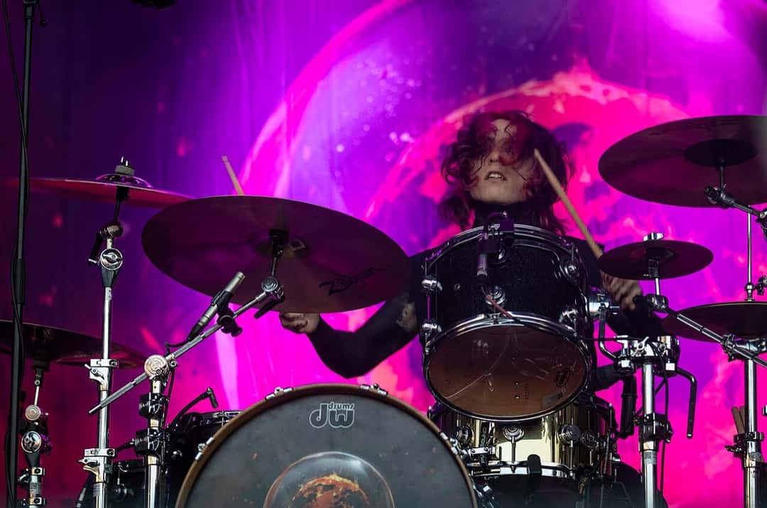 El baterista de Motionless In White toca en el festival Rock am Ring de 2023, detrás de los platillos y frente a una pantalla con luces rosas y violetas (foto de archivo). Foto: Andreas Lawen, CC0, vía Wikimedia Commons