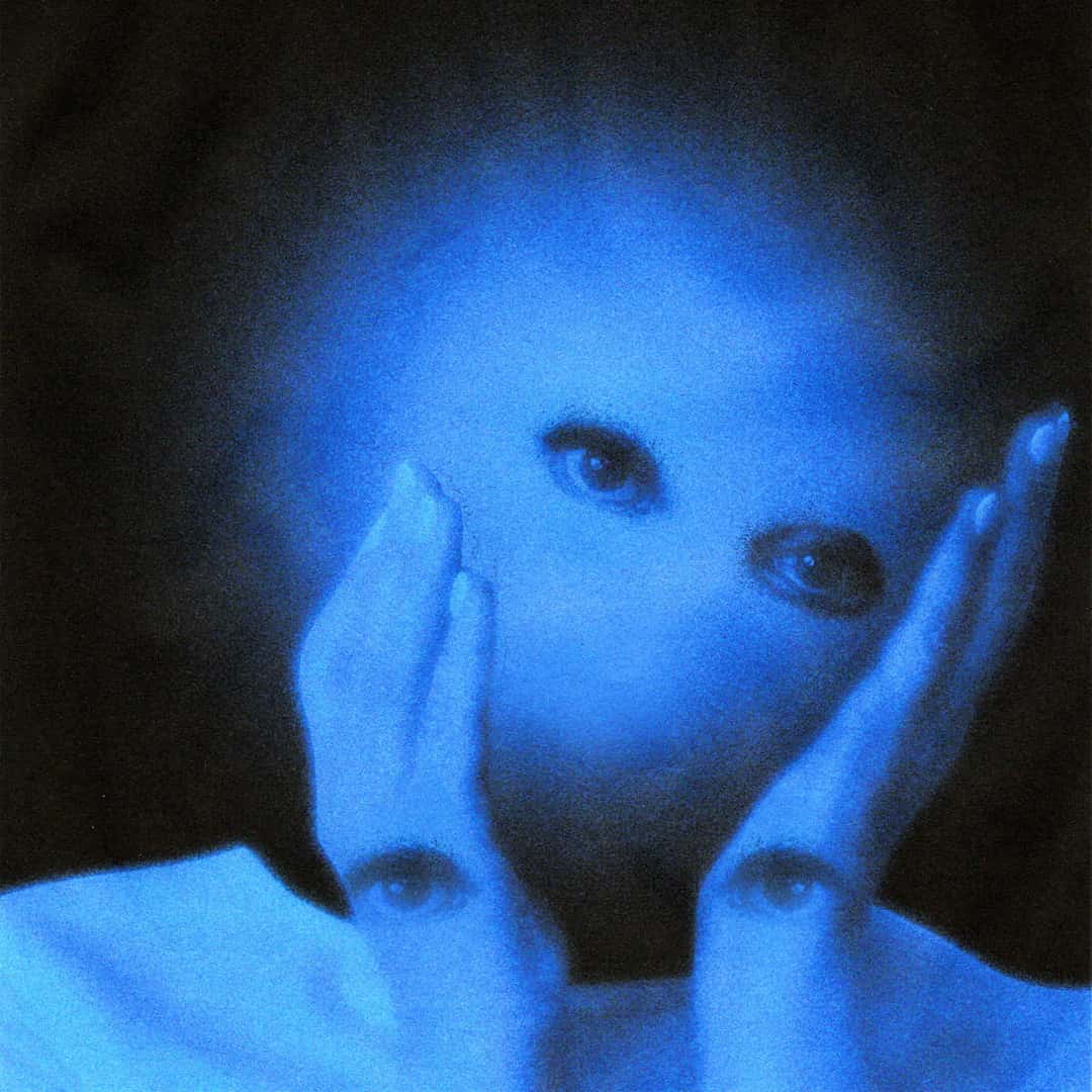 Portada de Heaven on Mars de NoCap: un rostro bañado en luz azul, con dos manos apoyadas en las mejillas que tienen ojos dibujados en las palmas, sobre fondo negro