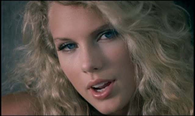 Taylor Swift en primer plano, con el pelo rubio enrulado, en el video oficial de «Tim McGraw» (fotograma del video oficial)