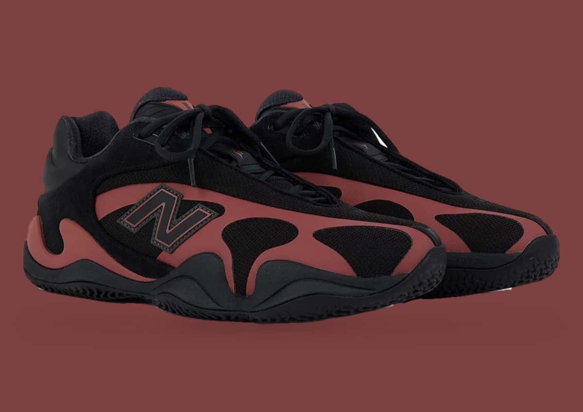 Par de New Balance Maxey V1 Red Rock negras con la jaula lateral en rojo ladrillo y la N negra con borde rojo, sobre fondo bordó