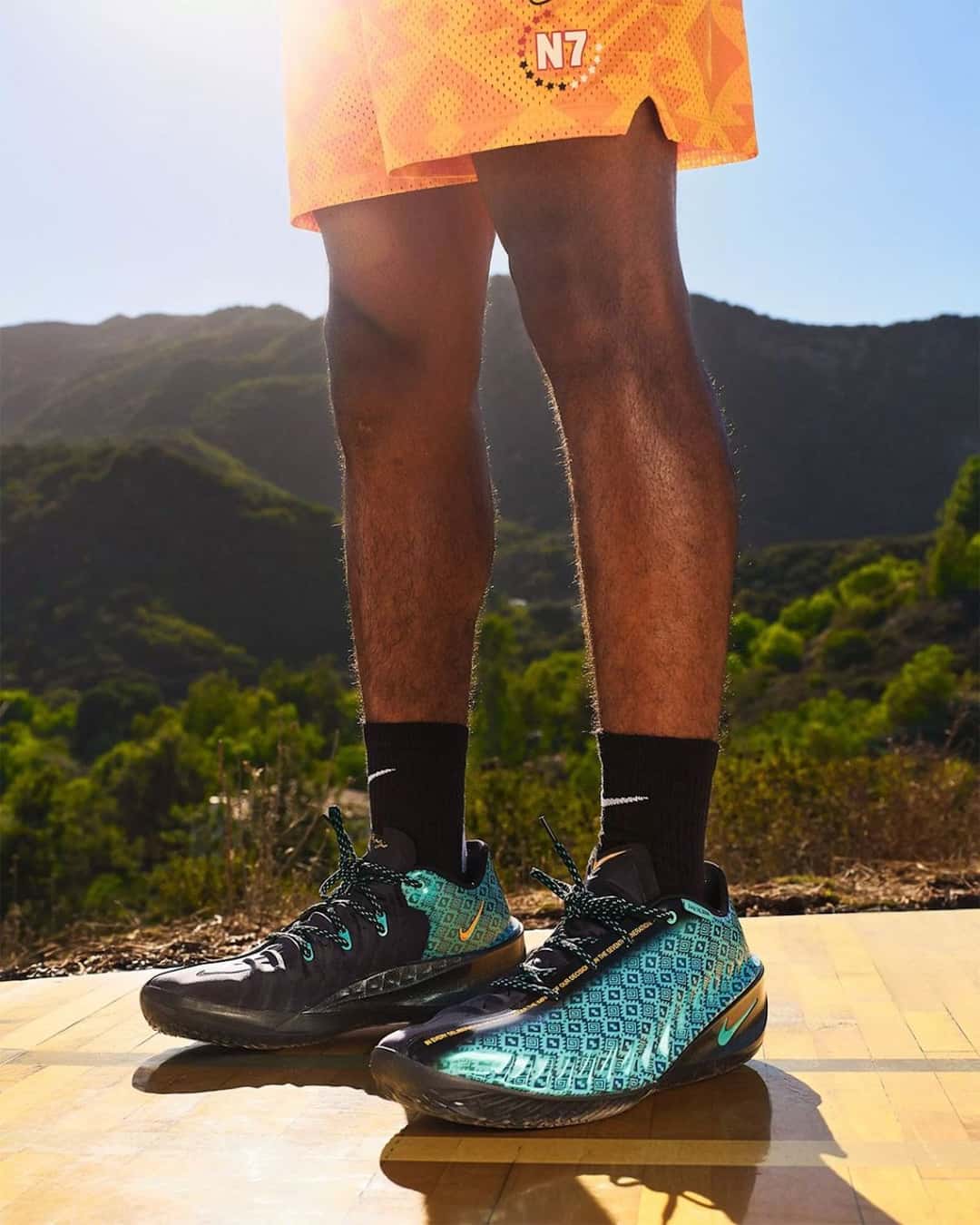 Nike G.T. Cut 4 N7 en turquesa y negro con estampado de espirales, puestas sobre un piso de madera al aire libre