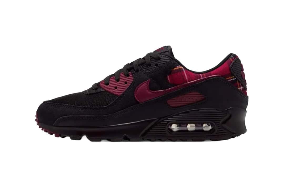 Nike Air Max 90 del Plaid Pack de perfil sobre fondo blanco, con base negra, ojales y Swoosh en rojo oscuro y tela escocesa roja en el cuello y el talón