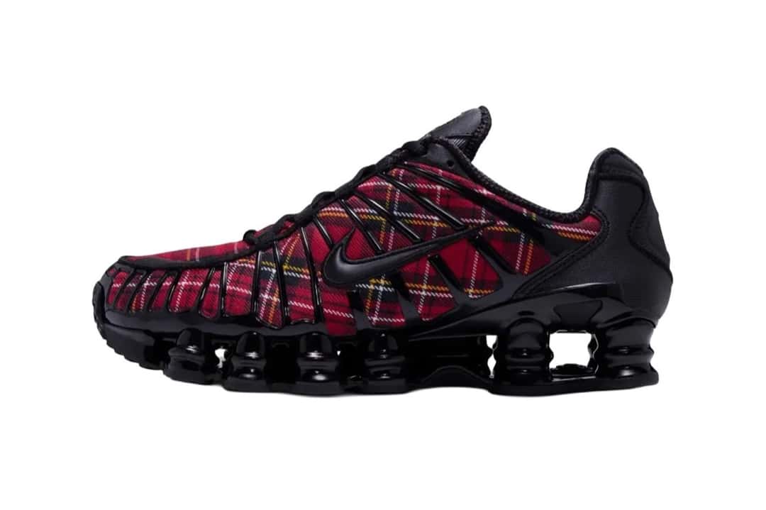 Nike Shox TL del Plaid Pack de perfil sobre fondo blanco, con tela escocesa roja debajo de la estructura negra y las columnas Shox negras