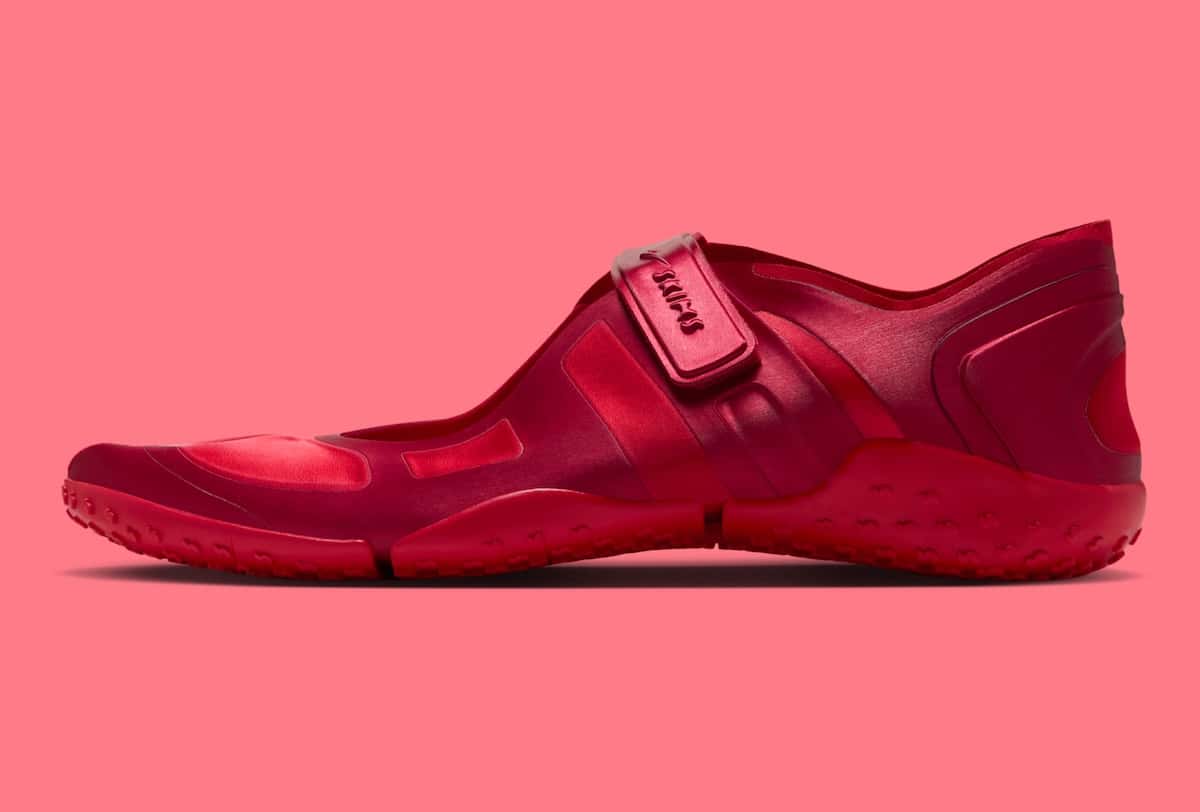 NikeSKIMS Rift Satin University Red de perfil sobre fondo rosa, con capellada de satén en varios tonos de rojo, abrojo con el swoosh y el logo SKIMS y suela roja segmentada