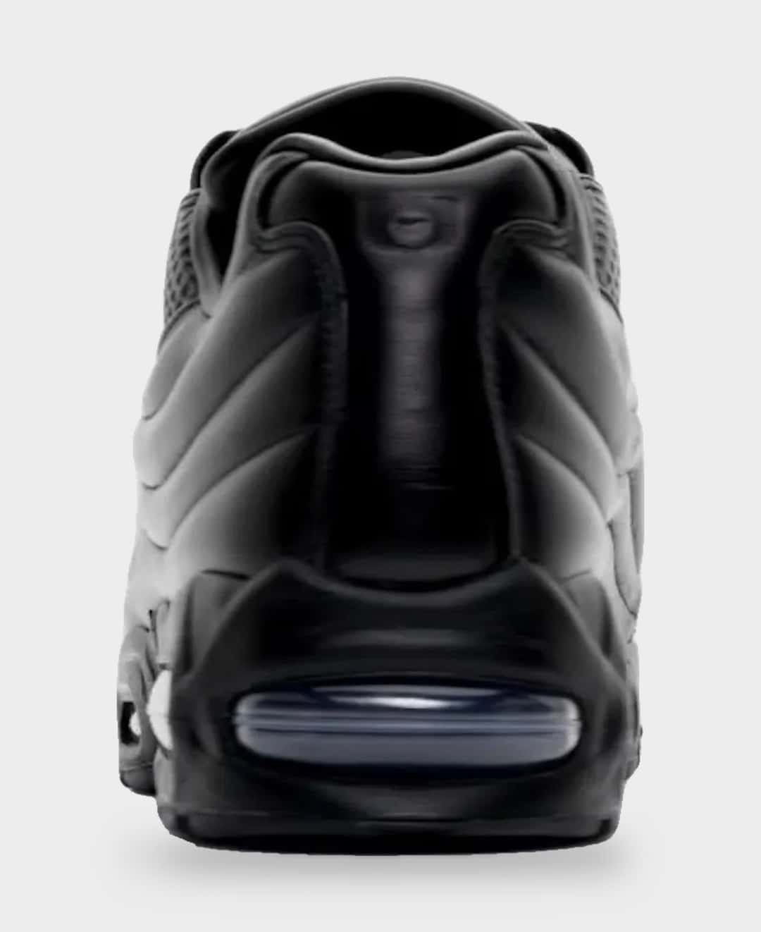 Talón de la Nike Air Max 95 Lux de One Block Down sobre fondo gris claro, todo en cuero negro, con la cámara Air azulada visible en la base