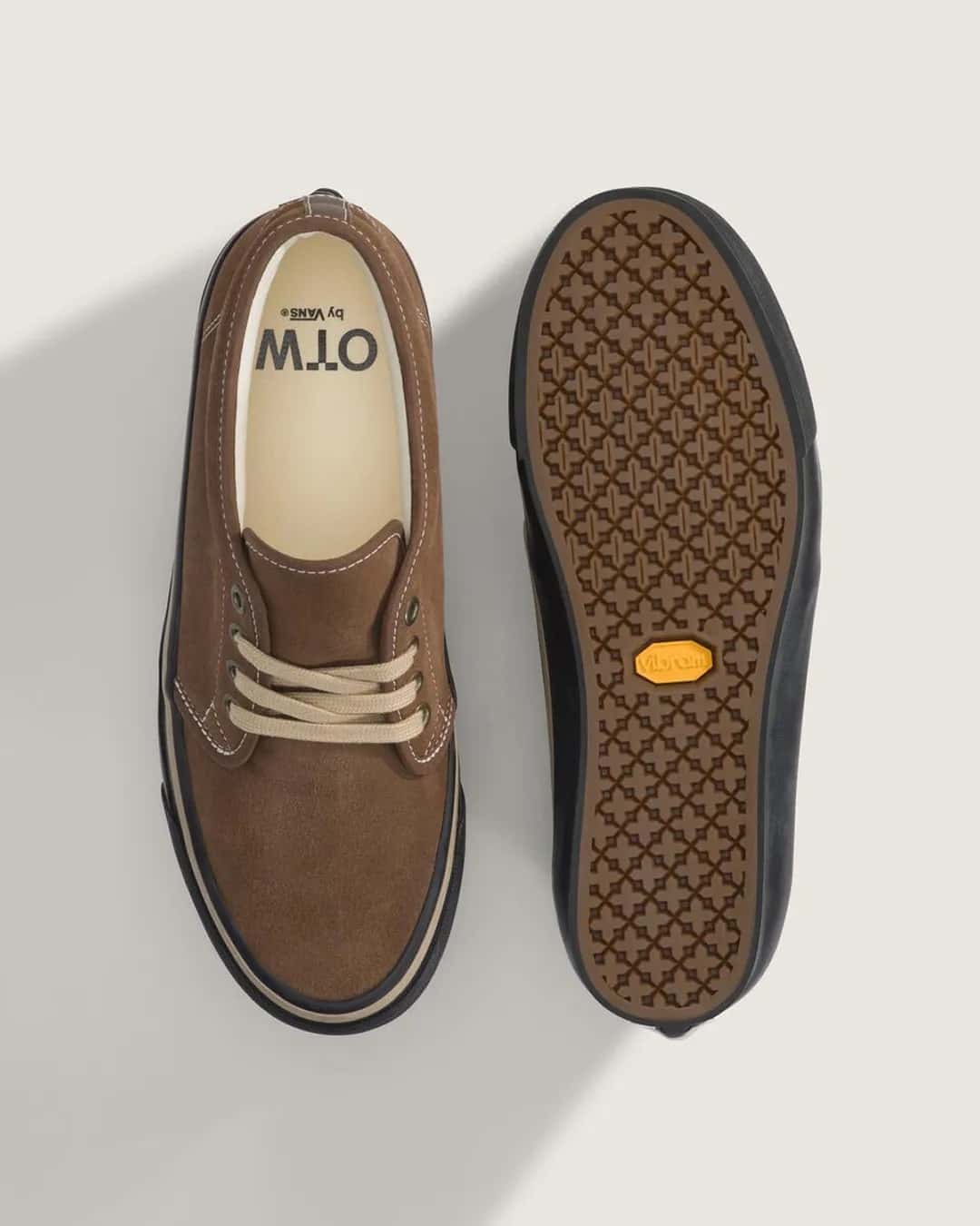 Vista desde arriba de la OTW by Vans Chukka 49 Vibram Vintage Cocoa junto a otra dada vuelta: a la izquierda la gamuza marrón con cordones beige y la plantilla con el logo OTW by Vans, a la derecha la suela con dibujo geométrico y el logo amarillo de Vibram