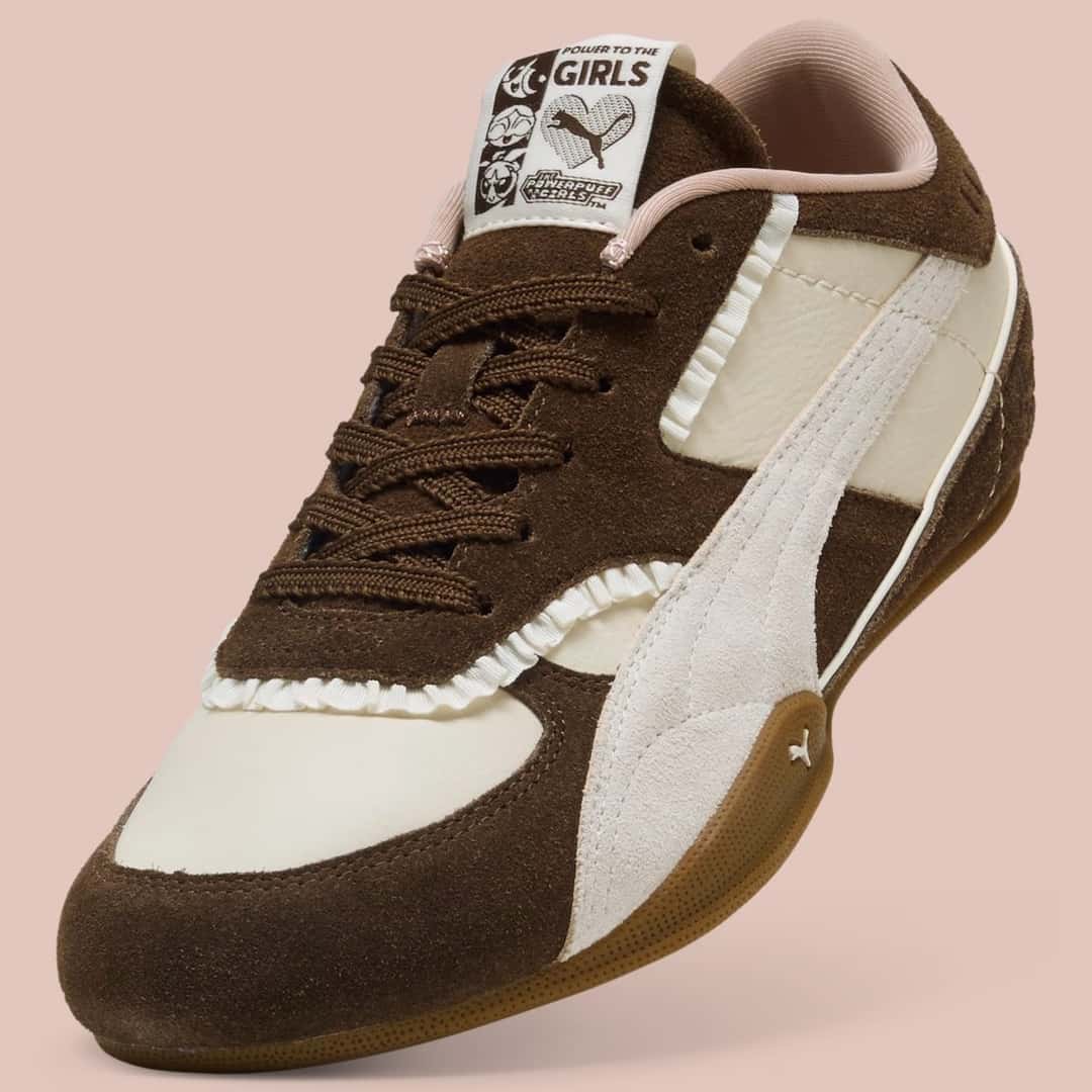 Detalle de la Puma Bella Mina x The Powerpuff Girls con la etiqueta de la lengüeta que muestra a las tres chicas, los volados blancos y la gamuza marrón