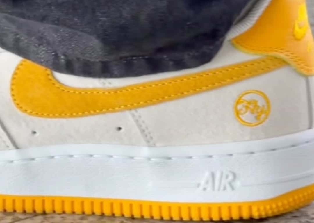 Detalle del Nike SB Air Force 1 de Fly Streetwear, con upper de gamuza clara, Swoosh de gamuza amarilla, logo circular de Fly bordado en amarillo en el talón y suela amarilla