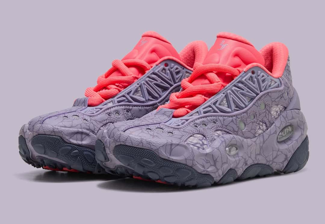Par de PUMA LaFrancé RNR Stranger Things sobre fondo lila, con upper violeta claro cubierto de grietas, perforaciones circulares, letras en relieve sobre el empeine, cordones gruesos y lengüeta en rojo coral, y suela gris oscuro con tacos redondeados