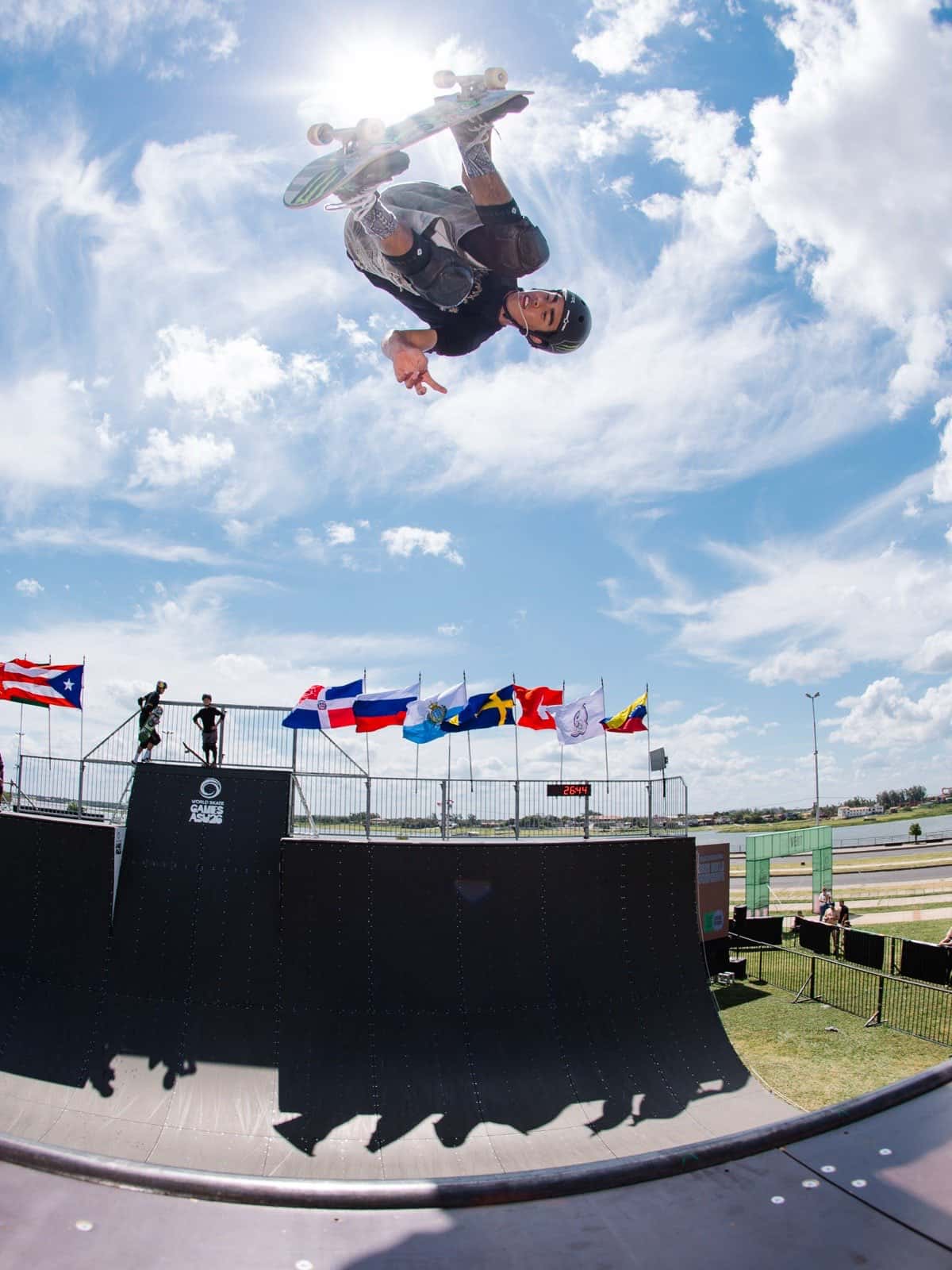 JD Sánchez vuela de cabeza sobre la rampa de vert de los World Skate Games ASU26, con banderas de distintos países detrás