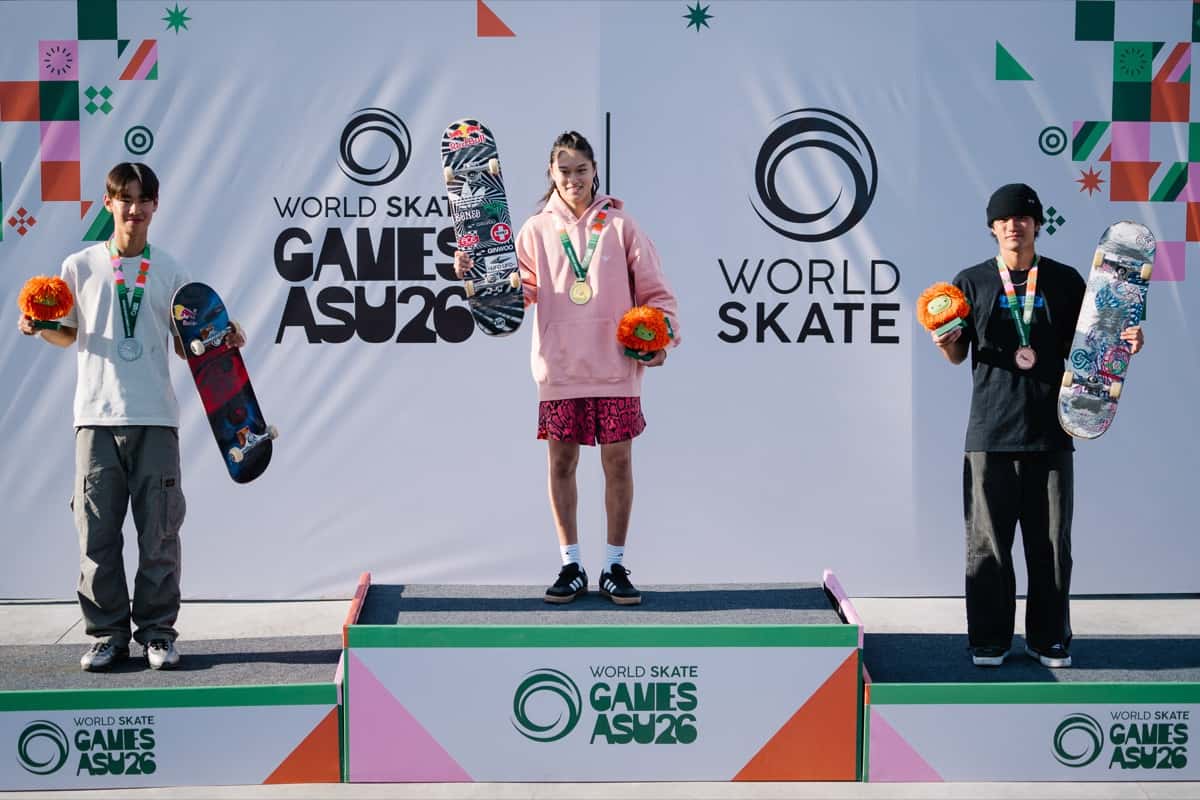 Podio del Mundial de street en Luque: Ginwoo Onodera, con buzo rosa y short rojo, en el escalón más alto con su medalla de oro, entre Juni Kang, a la izquierda, y Taiga Nagai, a la derecha, todos con flores naranjas y sus tablas en la mano