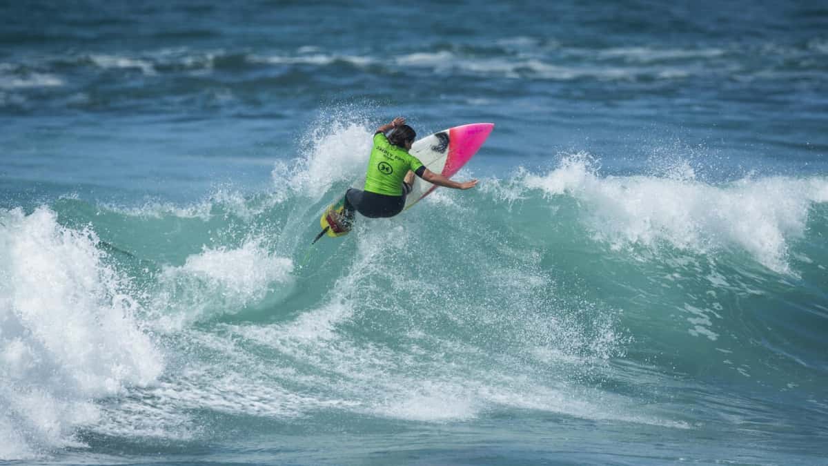 Mimi Barona, con lycra verde, gira con la tabla sobre la cresta de una ola en una fecha de la WSL (foto de archivo)