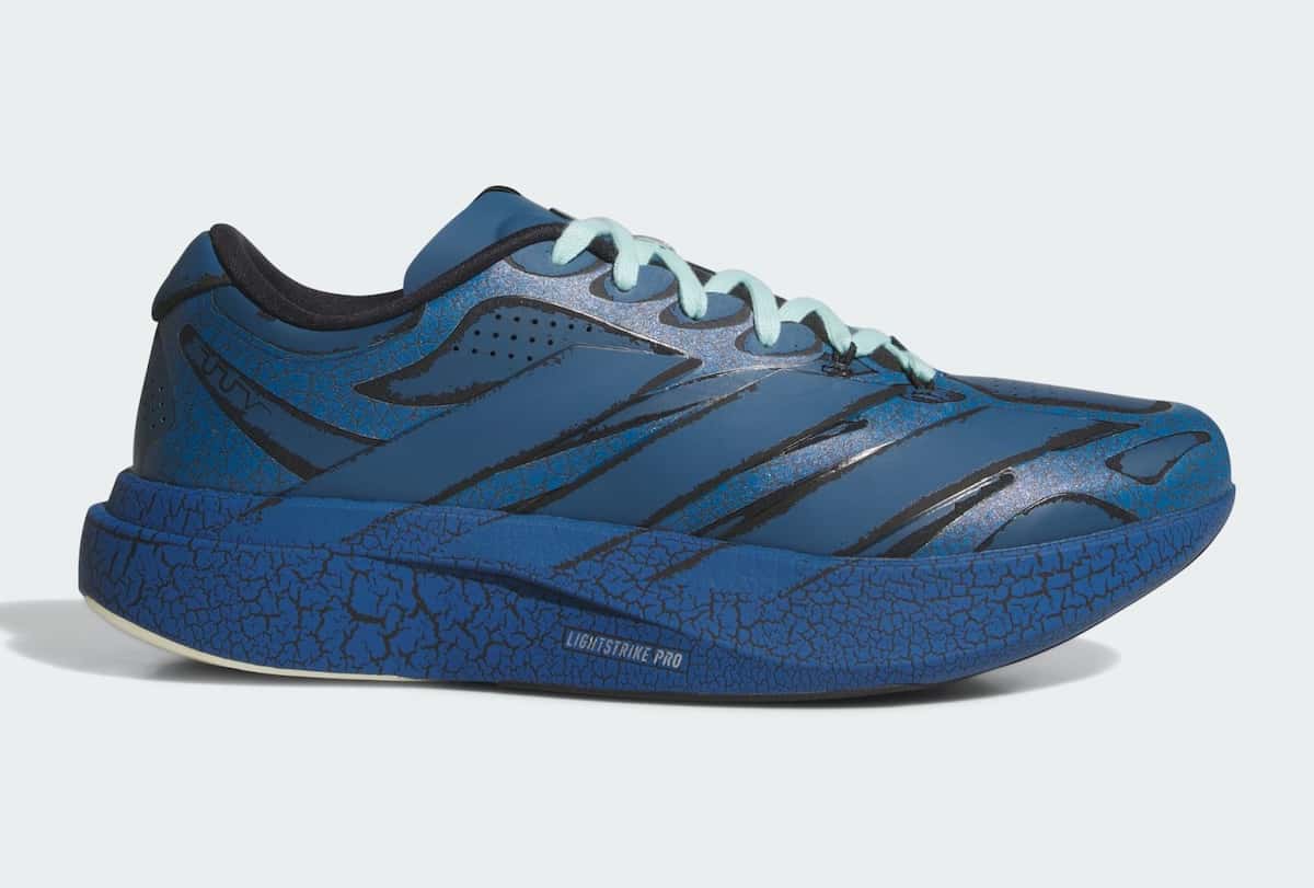 Adidas Adizero Evo SL Exo de The Whitaker Group en azul marino, de perfil sobre fondo gris claro, con líneas negras, estampado agrietado en la mediasuela y cordones celeste agua