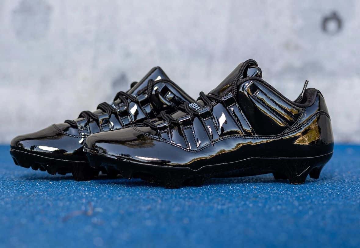 Par de botines Air Jordan 11 Gammas de UCLA en charol negro, apoyados sobre una superficie azul
