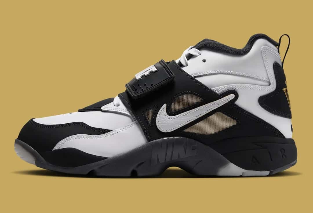 Nike Air DT Proto '92 de Well Off Forever de perfil sobre fondo dorado, con cuero blanco, paneles negros, correa negra sobre el empeine, Swoosh blanco en el lateral y suela negra